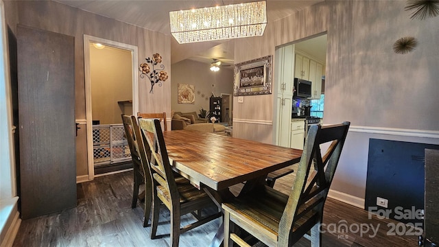 dining space featuring ceiling fan with notable chandelier and dark wood-type flooring