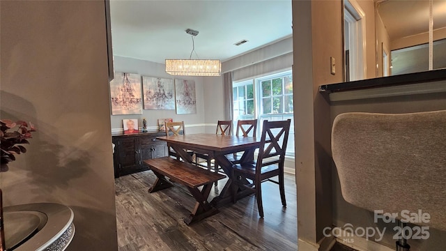 dining space with hardwood / wood-style flooring and a notable chandelier