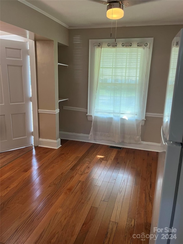 unfurnished dining area featuring ceiling fan, hardwood / wood-style flooring, and ornamental molding