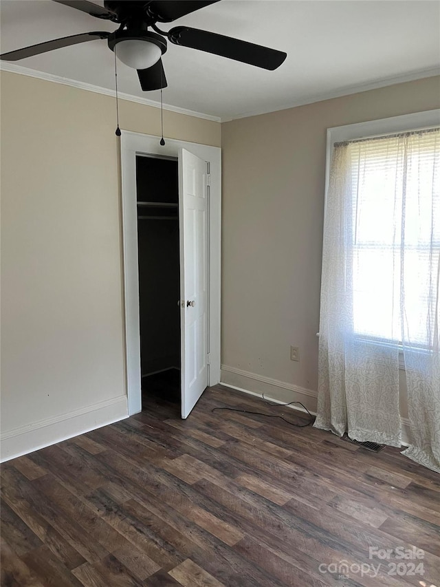 unfurnished bedroom with ceiling fan, a closet, dark hardwood / wood-style floors, and ornamental molding