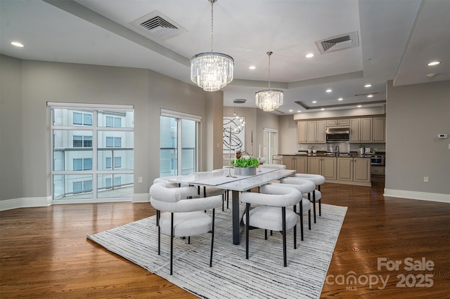 dining room featuring an inviting chandelier, a tray ceiling, and dark wood-type flooring