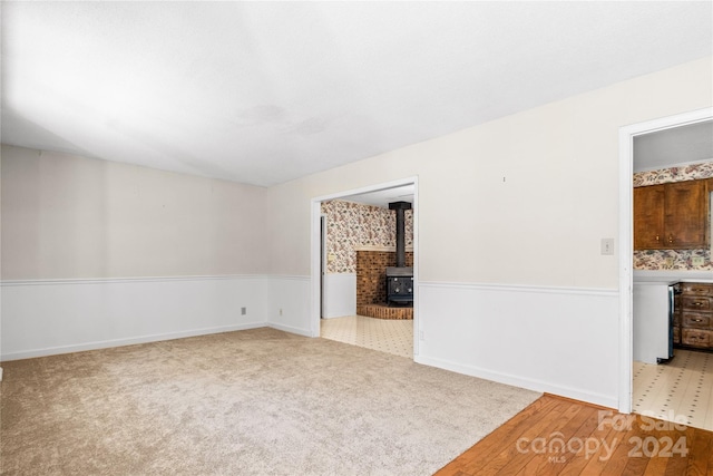 empty room with a wood stove and light wood-type flooring