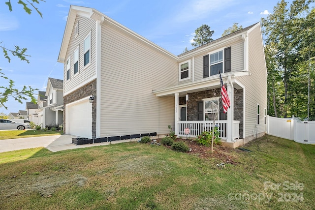 view of front facade featuring covered porch, a front yard, and a garage