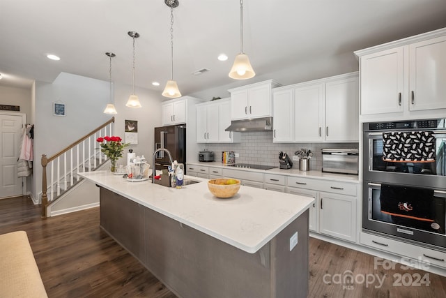 kitchen featuring appliances with stainless steel finishes, hanging light fixtures, white cabinets, a kitchen island with sink, and sink