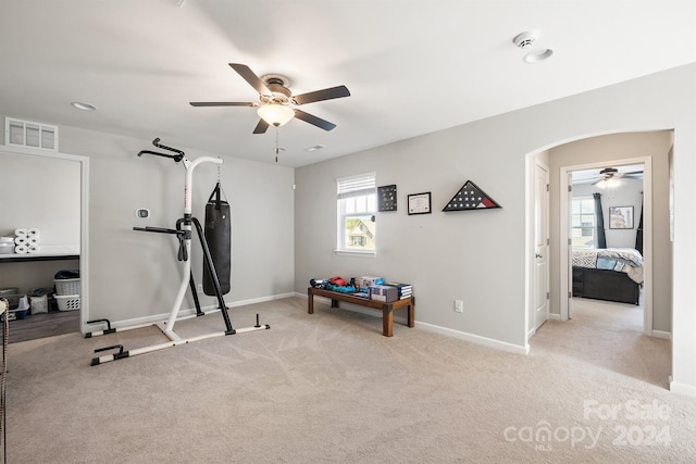 workout area with ceiling fan and light carpet