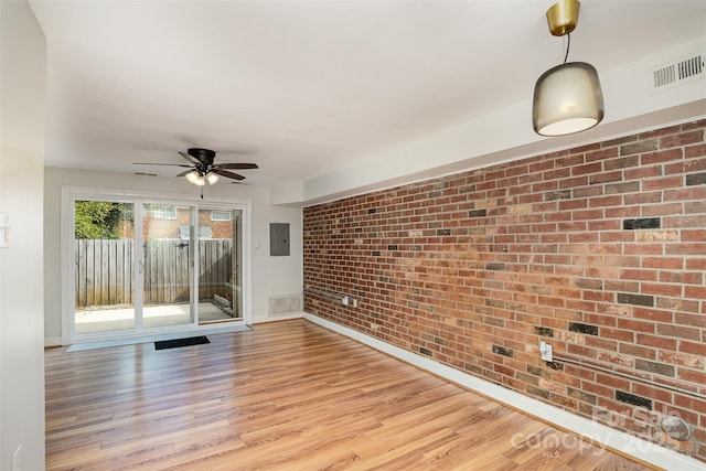 spare room with ceiling fan, brick wall, electric panel, and light hardwood / wood-style floors