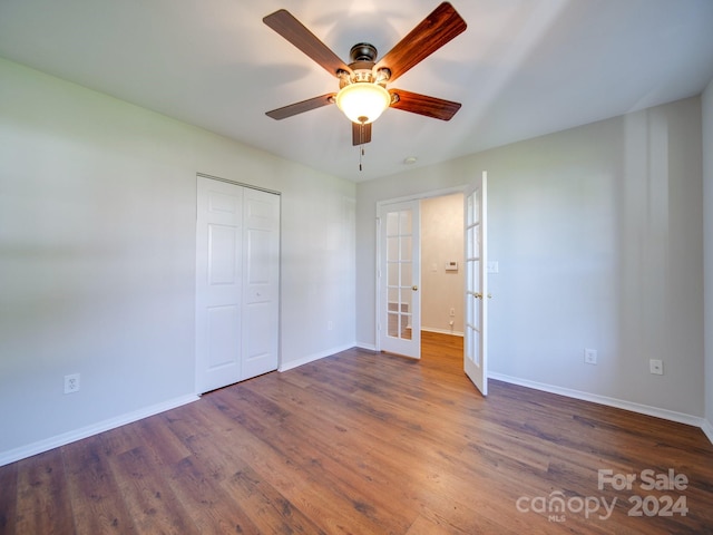 unfurnished bedroom with french doors, a closet, dark hardwood / wood-style floors, and ceiling fan