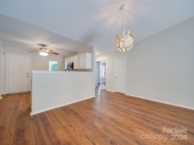 unfurnished living room featuring ceiling fan with notable chandelier and dark hardwood / wood-style floors