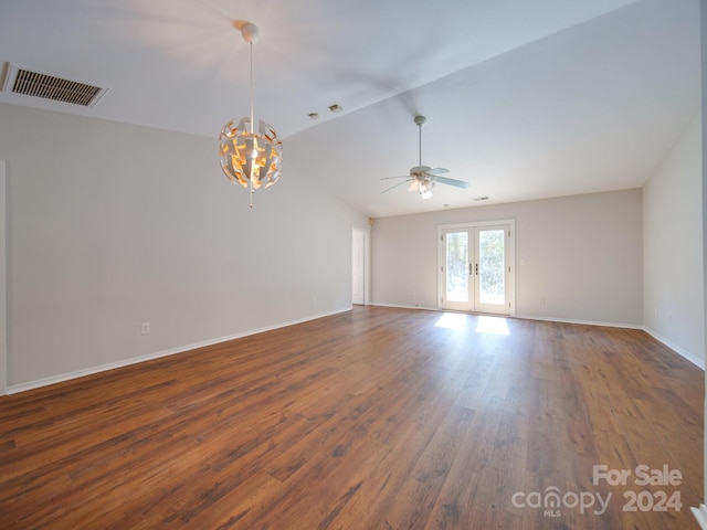 empty room with dark wood-type flooring, ceiling fan with notable chandelier, french doors, and lofted ceiling