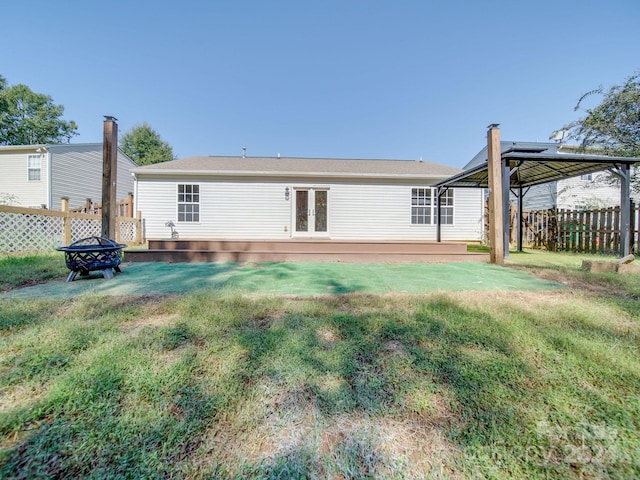 back of house with a yard and an outdoor fire pit