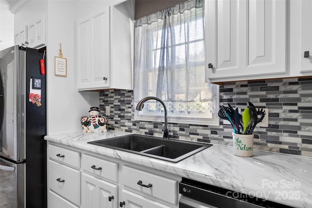 kitchen featuring sink, stainless steel fridge, tasteful backsplash, dishwashing machine, and white cabinetry