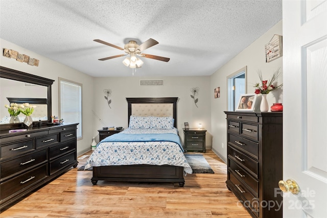 bedroom featuring ceiling fan, light hardwood / wood-style floors, and a textured ceiling