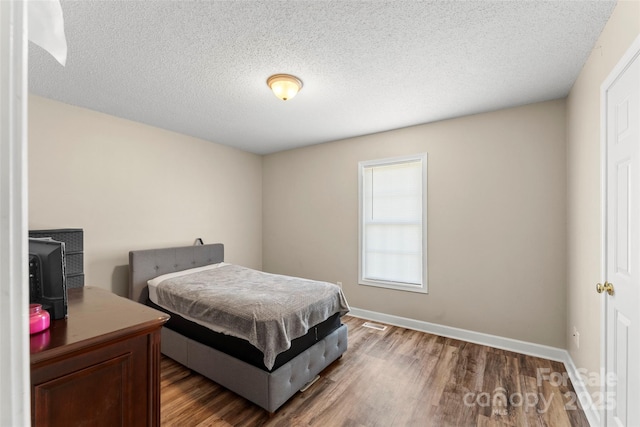 bedroom with dark hardwood / wood-style floors and a textured ceiling