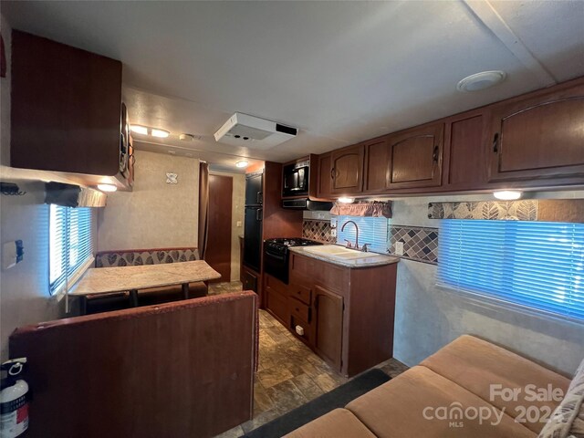 kitchen featuring backsplash, sink, and black microwave