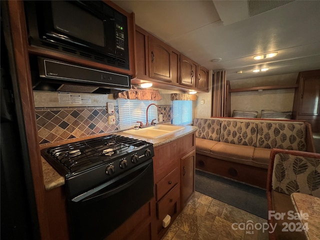 kitchen featuring decorative backsplash, black appliances, and sink