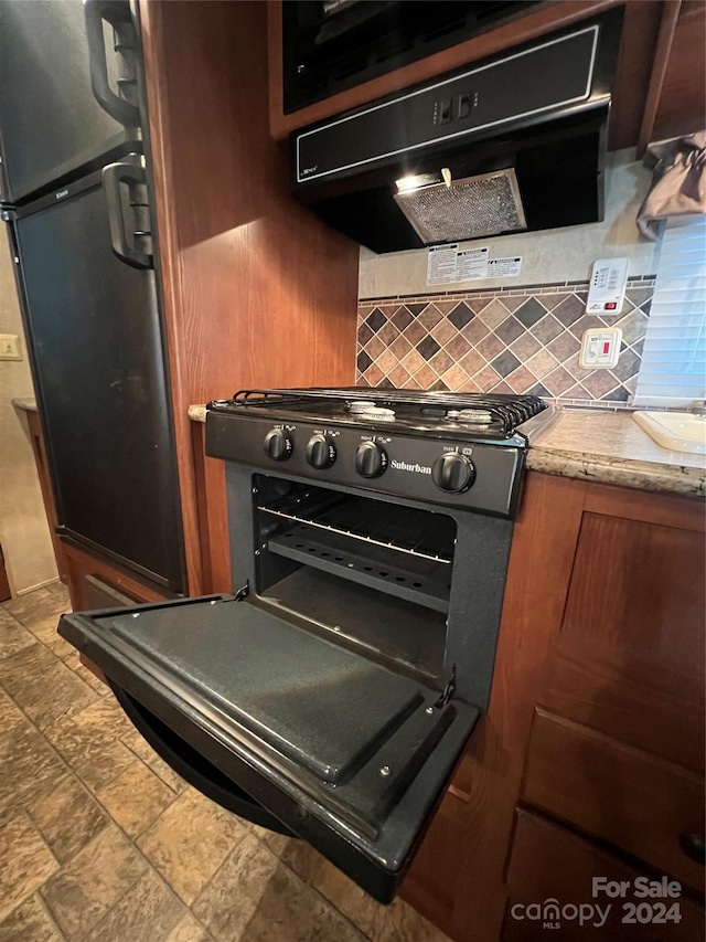 kitchen with light stone counters, ventilation hood, and decorative backsplash