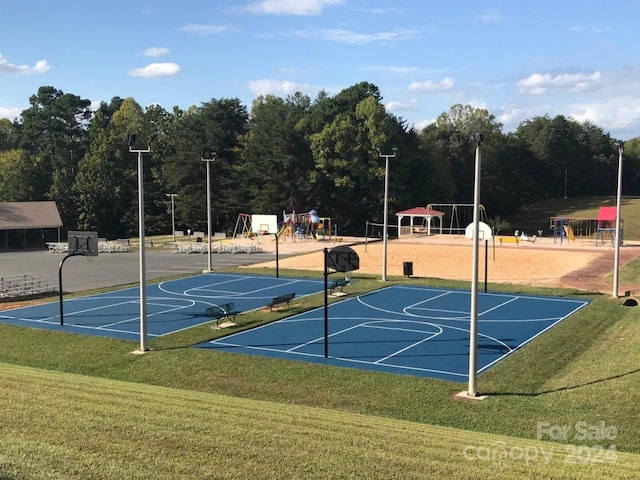 view of basketball court featuring a playground and a lawn