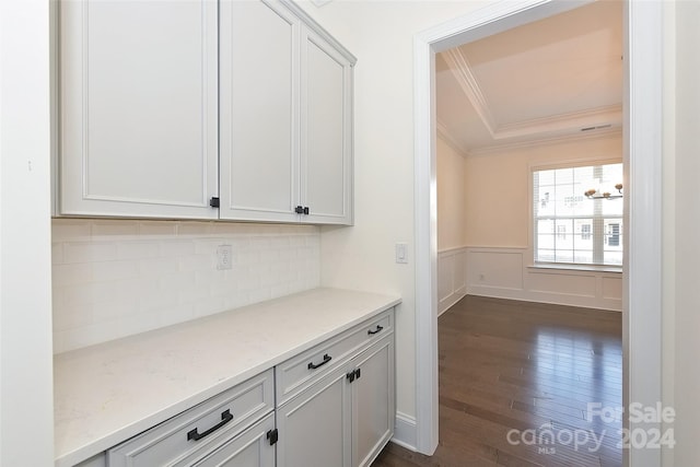 bar with white cabinets, backsplash, ornamental molding, dark hardwood / wood-style floors, and light stone counters