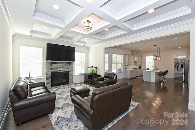 living room with coffered ceiling, a stone fireplace, beam ceiling, dark wood-type flooring, and crown molding