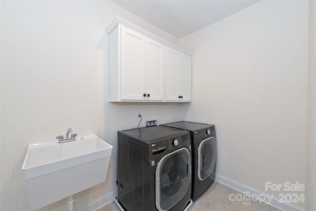 clothes washing area featuring independent washer and dryer, cabinets, sink, and light tile patterned floors