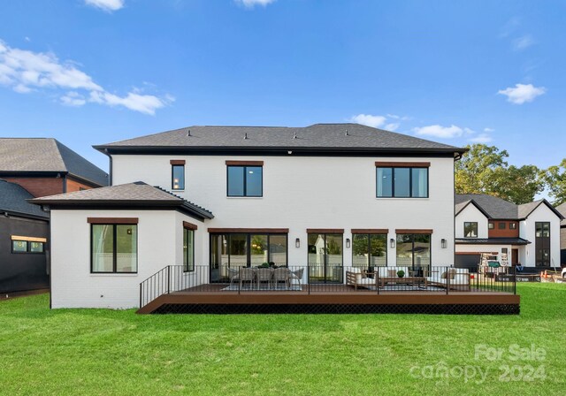 back of house featuring a lawn and a wooden deck