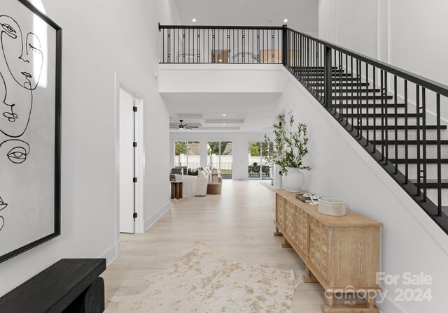 foyer with a high ceiling, ceiling fan, and light hardwood / wood-style flooring