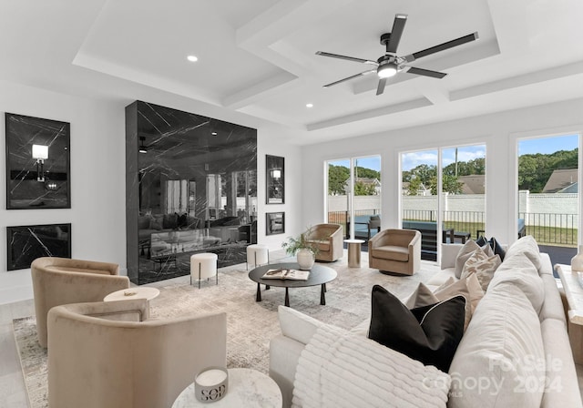 living room with ceiling fan, a raised ceiling, and light hardwood / wood-style flooring