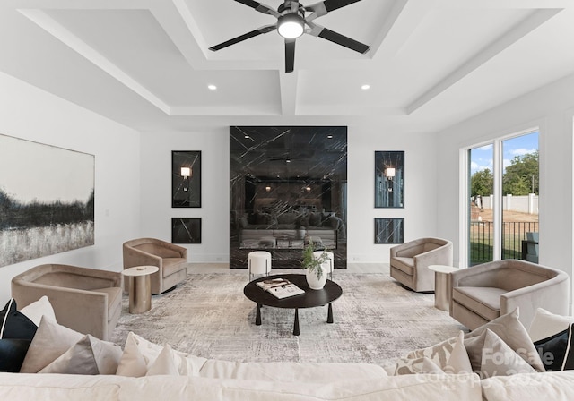 living room with a high end fireplace, ceiling fan, and a raised ceiling