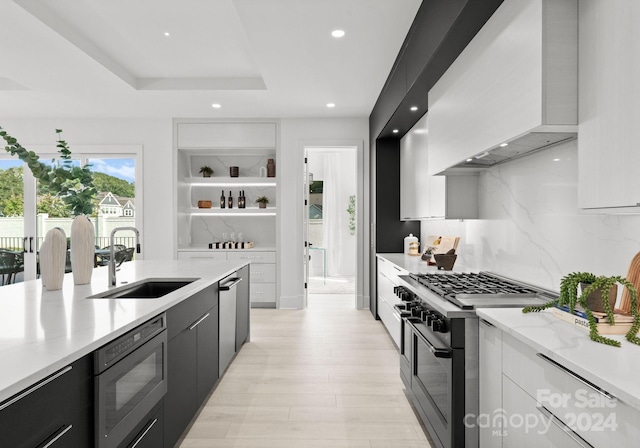 kitchen with stainless steel appliances, tasteful backsplash, white cabinets, premium range hood, and sink