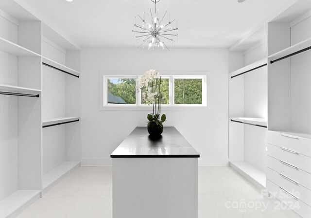 walk in closet featuring an inviting chandelier and light tile patterned floors