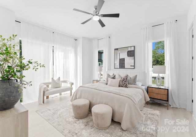 bedroom with ceiling fan, light hardwood / wood-style floors, and multiple windows