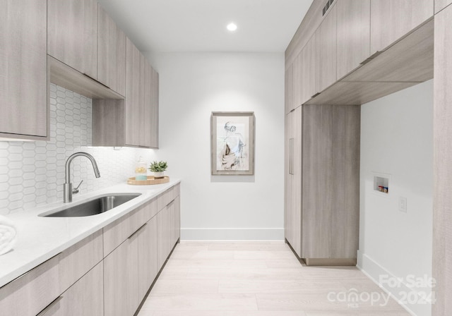 kitchen with light brown cabinetry, light hardwood / wood-style flooring, sink, and decorative backsplash