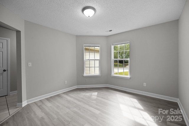 empty room featuring a textured ceiling and light hardwood / wood-style flooring