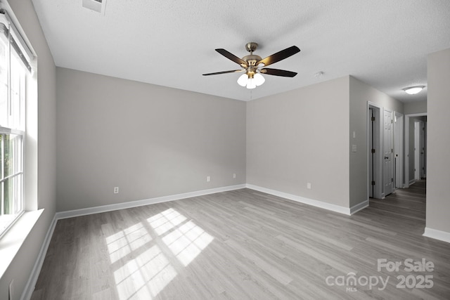 unfurnished room with ceiling fan, a healthy amount of sunlight, a textured ceiling, and light wood-type flooring