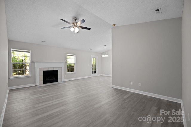 unfurnished living room featuring plenty of natural light, a fireplace, wood-type flooring, and lofted ceiling