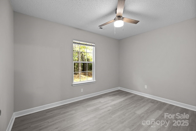 spare room with ceiling fan, a textured ceiling, and light wood-type flooring