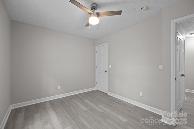 spare room featuring ceiling fan, light hardwood / wood-style floors, and a textured ceiling