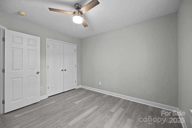 unfurnished bedroom featuring ceiling fan, light hardwood / wood-style flooring, a textured ceiling, and a closet