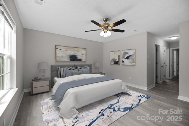 bedroom with multiple windows, ceiling fan, and light wood-type flooring