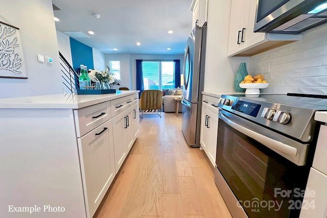 kitchen with light hardwood / wood-style flooring, appliances with stainless steel finishes, tasteful backsplash, and white cabinetry