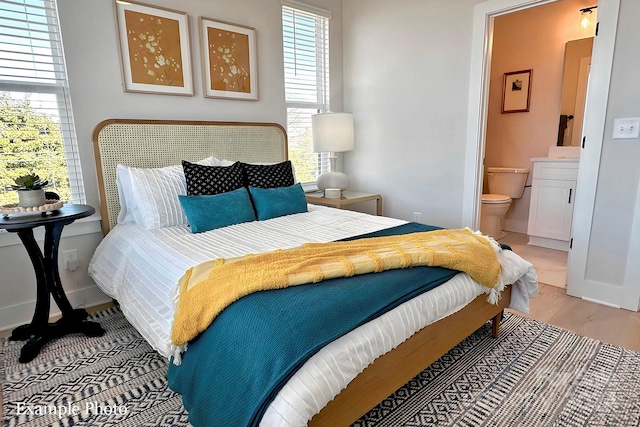 bedroom with light wood-type flooring and ensuite bathroom