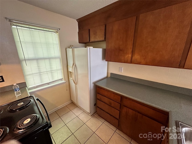 kitchen featuring white fridge with ice dispenser, range with electric stovetop, and light tile patterned floors