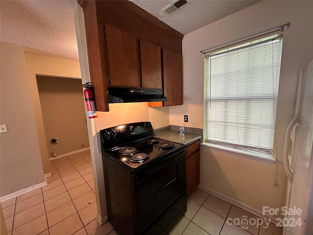 kitchen with a wealth of natural light, a textured ceiling, black / electric stove, and light tile patterned flooring