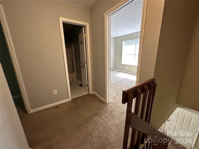 corridor with a textured ceiling and carpet