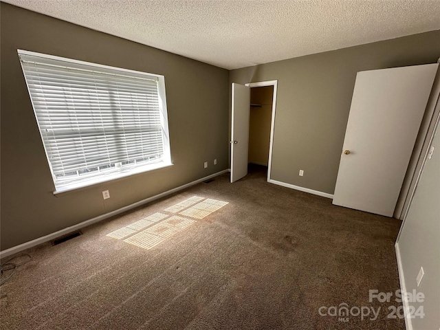 unfurnished bedroom with dark carpet and a textured ceiling