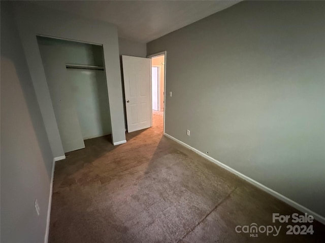 unfurnished bedroom featuring dark colored carpet and a closet