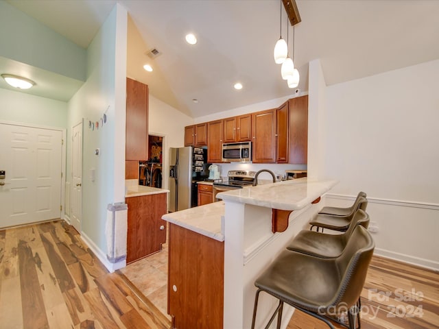 kitchen with light wood-type flooring, a kitchen breakfast bar, stainless steel appliances, kitchen peninsula, and hanging light fixtures