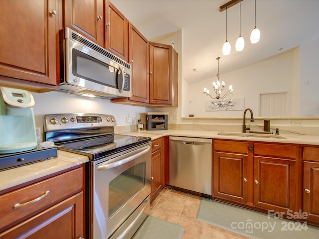 kitchen featuring pendant lighting, light tile patterned floors, sink, stainless steel appliances, and vaulted ceiling