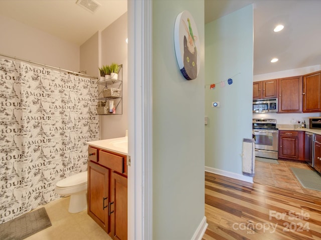 bathroom featuring a shower with curtain, wood-type flooring, vanity, and toilet