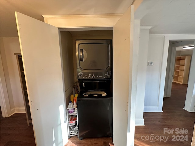 laundry room with dark hardwood / wood-style floors, stacked washer / drying machine, and crown molding